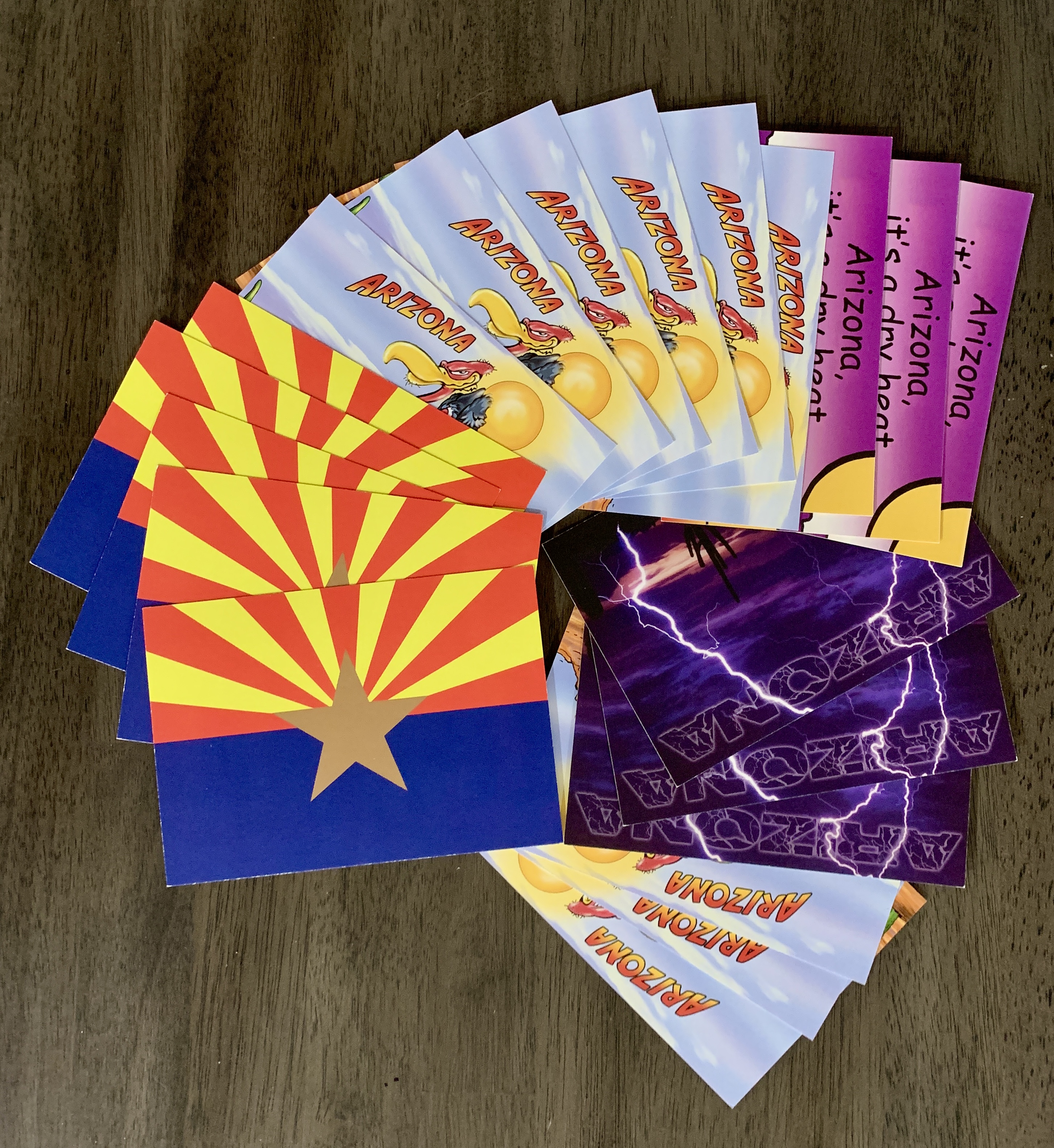 Fanned-out Arizona postcards showing the state flag, desert scenes and “Arizona, it’s a dry heat”