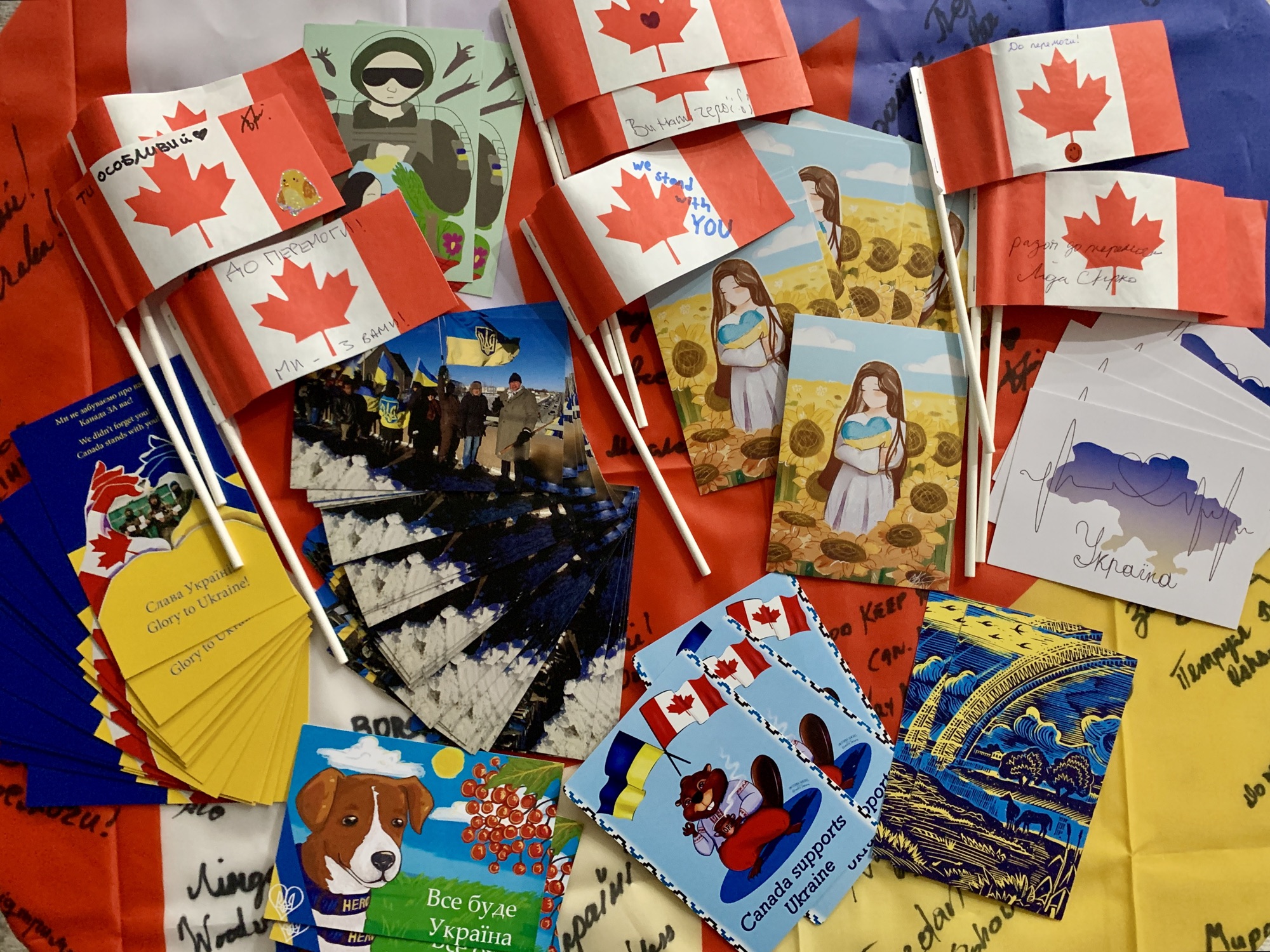 Postcards, children’s artwork and small Canadian paper flags spread over Ukrainian flag fabric